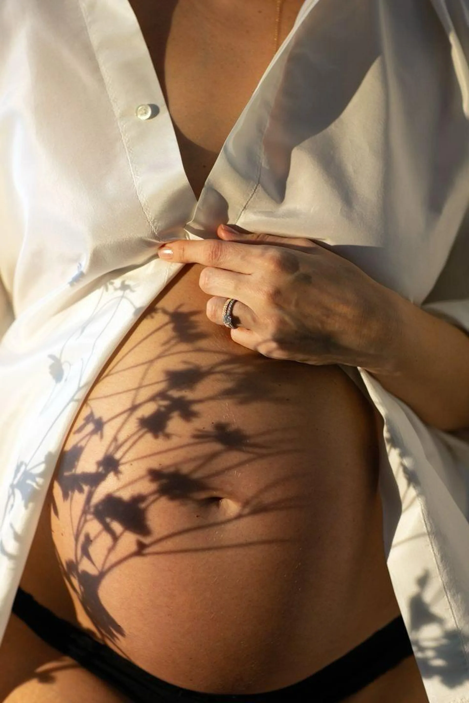 Un ventre de femme enceinte, ombre portée d’un feuillage